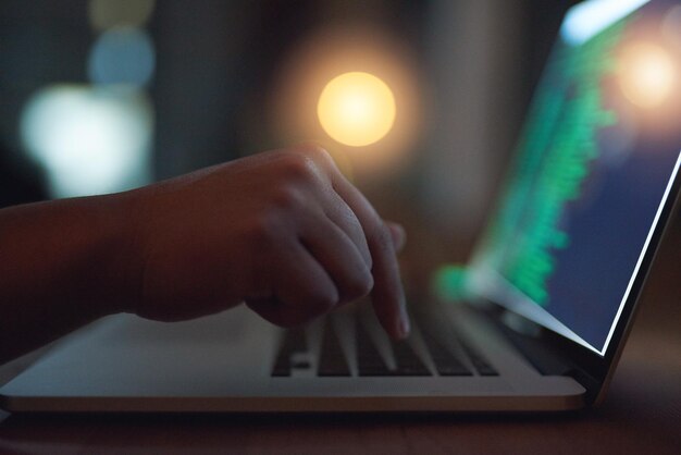 A close-up shot of hands typing on a laptop keyboard, with a focus on the fingers and the illuminated screen, symbolizing digital skills training and online job resources.