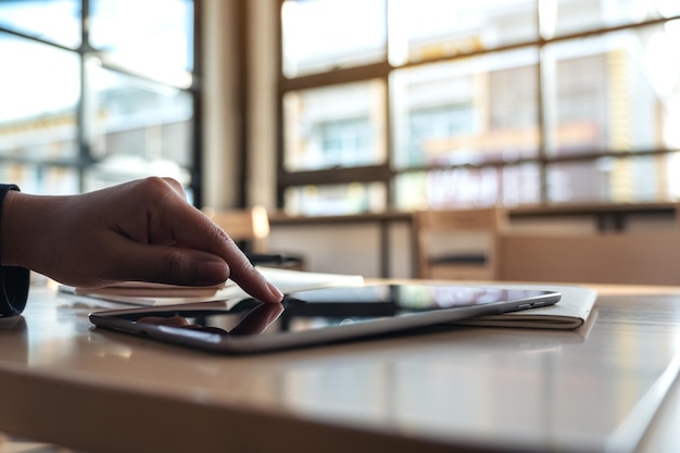 A close-up shot of hands working on a tax form with a magnifying glass hovering over the document. The background is blurred with a glimpse of a home office setup.